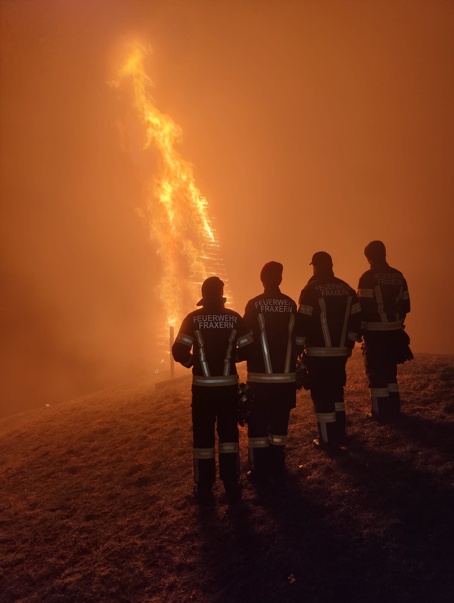 Vier Kameraden der Ortsfeuerwehr Fraxern vor dem Funkenfeuer